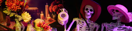 Halloween floral display with orange and red flowers, glowing candles, skeleton decorations in hats, and dark seasonal d&eacute;cor