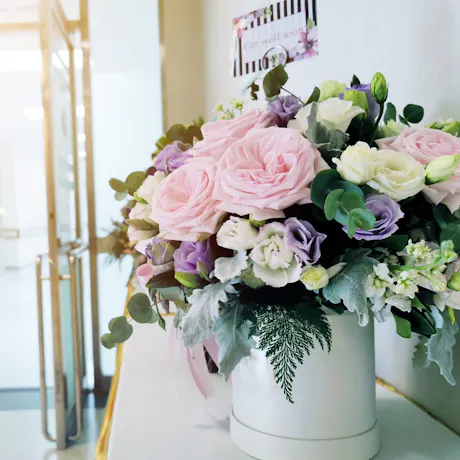 Pastel get well flower arrangement with pink roses, white and lavender blooms, eucalyptus, greenery, and a 